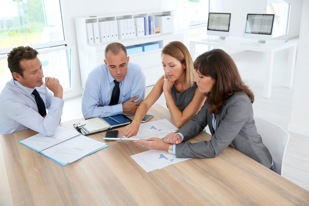 An executive team in an open, energised conversation around a table, illustrating the trust signals of a high-performing team.